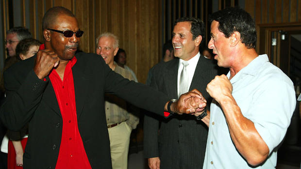 Actors Carl Weathers, left, and Sylvester Stallone pose at an album release party for singer Frank Stallone, center, at Capital Records on Aug. 7, 2003, in Hollywood, California. 