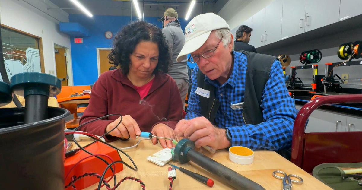 At a "fix it clinic" in California, volunteers assist community members in repairing damaged electronic devices.