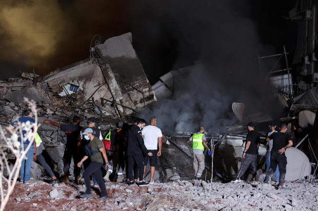 People inspect damage at the site of an Israeli strike in Beirut 