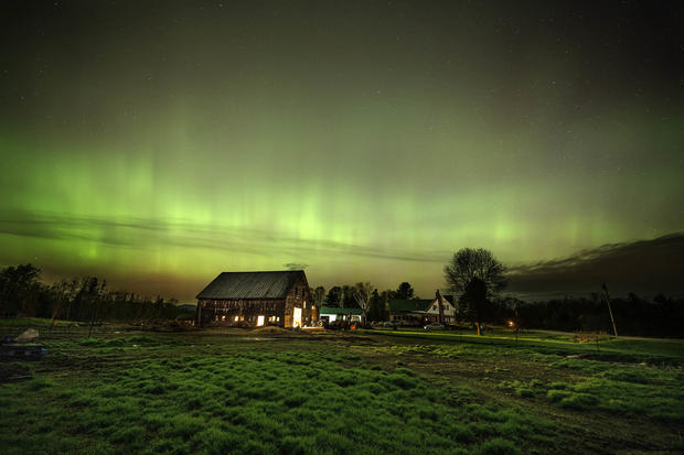 The northern lights fill the sky with green over the barn and pastures at Greaney's Turkey Farm in Mercer, Maine, on May 11, 2024. 